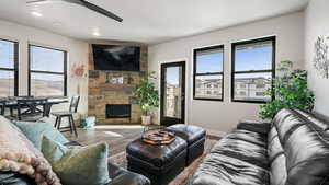 Living area featuring wood finished floors, plenty of natural light, ceiling fan, a stone fireplace, and recessed lighting