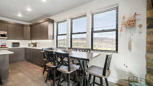 Kitchen featuring light countertops, dark brown cabinetry, light wood finished floors, stainless steel microwave, and modern cabinets