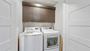 Washroom featuring cabinet space and washer and clothes dryer