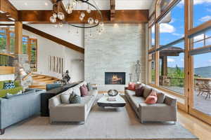 Living area featuring healthy amount of natural light, a stone fireplace, a towering ceiling, wood finished floors, and arched walkways
