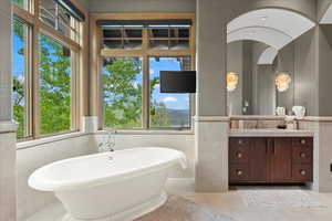 Bathroom with vanity, tile walls, a freestanding tub, light tile patterned floors, and healthy amount of natural light
