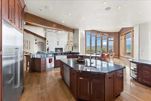 Kitchen featuring a mountain view, stainless steel appliances, dark stone counters, a large fireplace, and light wood-type flooring