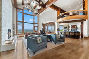 Living area featuring a fireplace, a chandelier, wood finished floors, beamed ceiling, and arched walkways