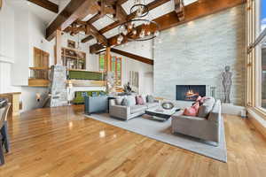 Living area featuring a high ceiling, a fireplace, light wood-style flooring, and beamed ceiling