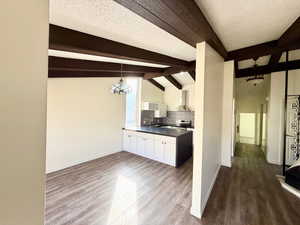 Kitchen featuring dark countertops, decorative backsplash, pendant lighting, dark wood-style floors, and beamed ceiling