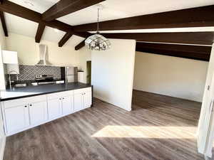 Kitchen featuring dark countertops, white cabinetry, stainless steel appliances, decorative backsplash, and light wood-type flooring
