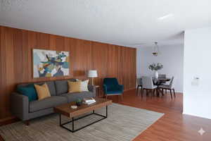 Living area with wood finished floors, wooden walls, and a textured ceiling