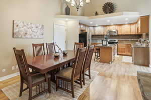 Dining space featuring recessed lighting, light wood-type flooring, a towering ceiling, and a chandelier