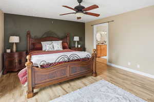 Primary bedroom featuring connected bathroom, ceiling fan, light wood-type flooring, and a textured ceiling