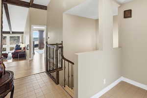 Hallway with an upstairs landing and light tile patterned floors