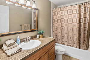 Bathroom featuring vanity, light tile patterned floors, a textured ceiling, and shower / bath combination with curtain