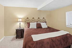 Carpeted bedroom featuring a textured ceiling and baseboards