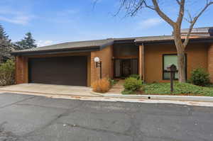 View of front of home with brick siding, driveway, and a garage