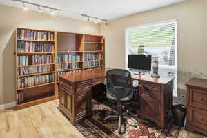 Home office with light wood-style flooring and rail lighting