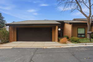 View of front of home with brick siding, a shingled roof, and driveway