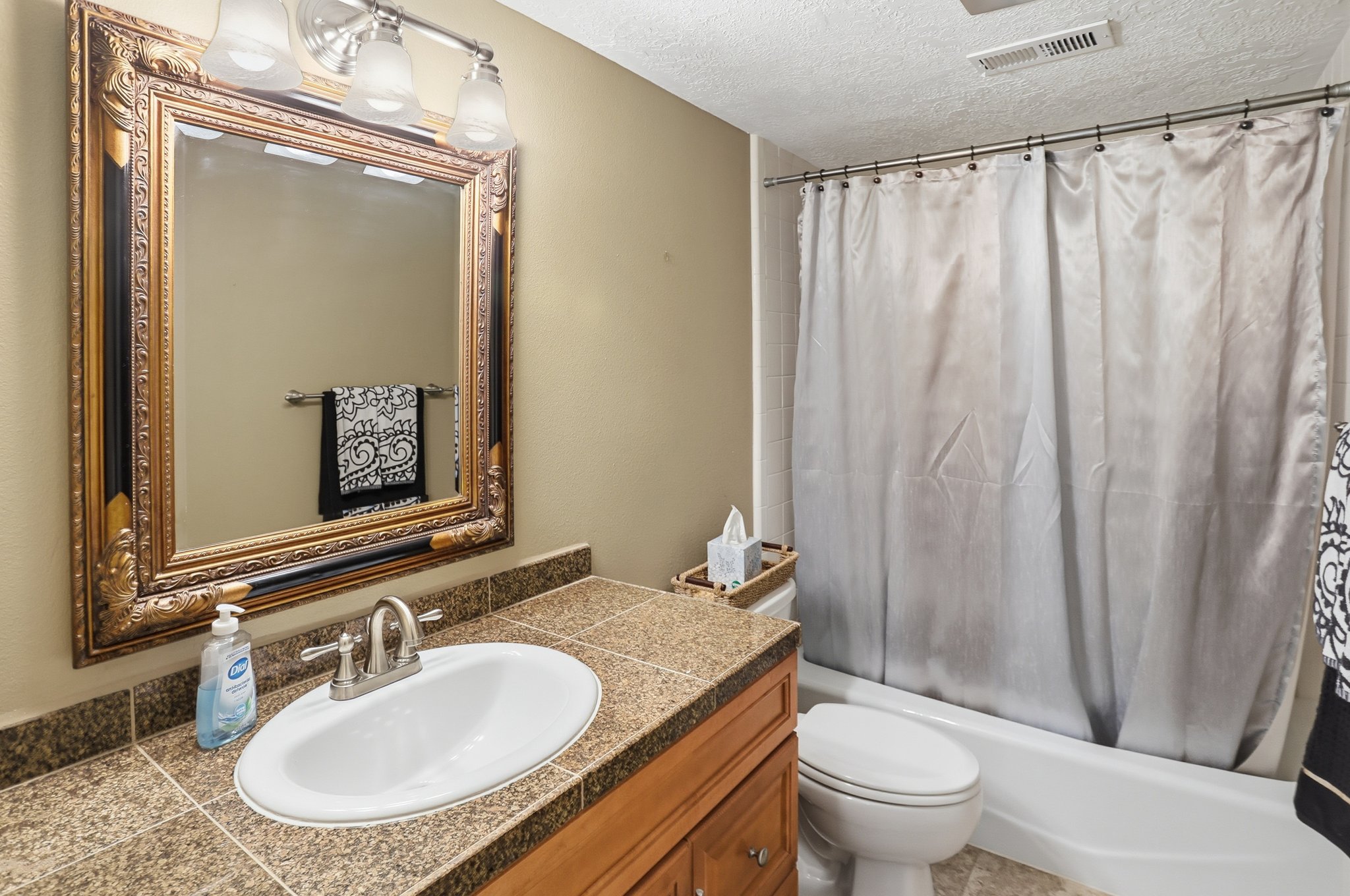 Bathroom with shower / tub combo with curtain, a textured ceiling, and vanity