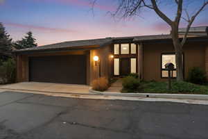 Mid-century home featuring brick siding, a garage, driveway, and a shingled roof