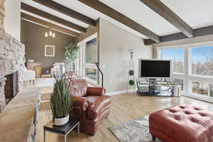 Living room with a fireplace, a chandelier, wood finished floors, and healthy amount of natural light