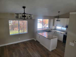 Kitchen featuring white cabinetry, pendant lighting, light stone countertops, dark wood finished floors, and a textured ceiling