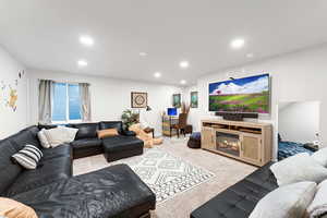 Living area featuring carpet, recessed lighting, and a glass covered fireplace