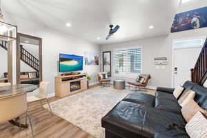 Living area with stairs, wood finished floors, recessed lighting, ceiling fan, and a glass covered fireplace