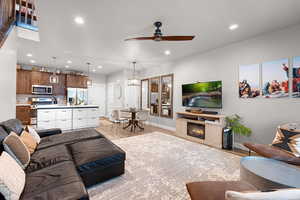 Living room featuring ceiling fan, light wood-style flooring, recessed lighting, and a glass covered fireplace