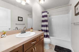 Bathroom with vanity, shower / bathtub combination with curtain, and light tile patterned floors