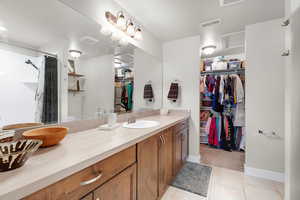 Full bathroom featuring a walk in closet, vanity, light tile patterned floors, a shower with shower curtain, and light carpet