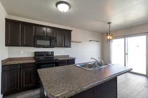 Kitchen featuring black appliances, dark brown cabinetry, dark wood-style floors, and dark countertops