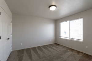Carpeted spare room featuring baseboards