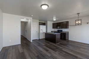 Kitchen with dark brown cabinetry, black appliances, pendant lighting, dark wood-style floors, and a center island with sink