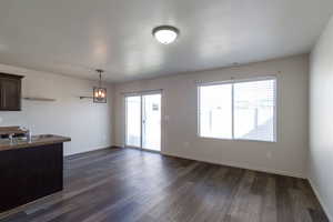 Kitchen featuring dark brown cabinetry, decorative light fixtures, dark wood-type flooring, and dark countertops