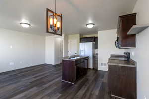 Kitchen featuring dark brown cabinets, decorative light fixtures, range, dark wood finished floors, and a chandelier