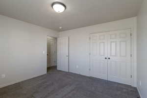 Unfurnished bedroom featuring dark colored carpet and a closet