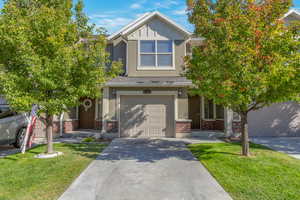 Craftsman-style house featuring brick siding, concrete driveway, board and batten siding, and a front lawn
