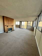 Unfurnished living room featuring a textured ceiling, a fireplace, and carpet flooring