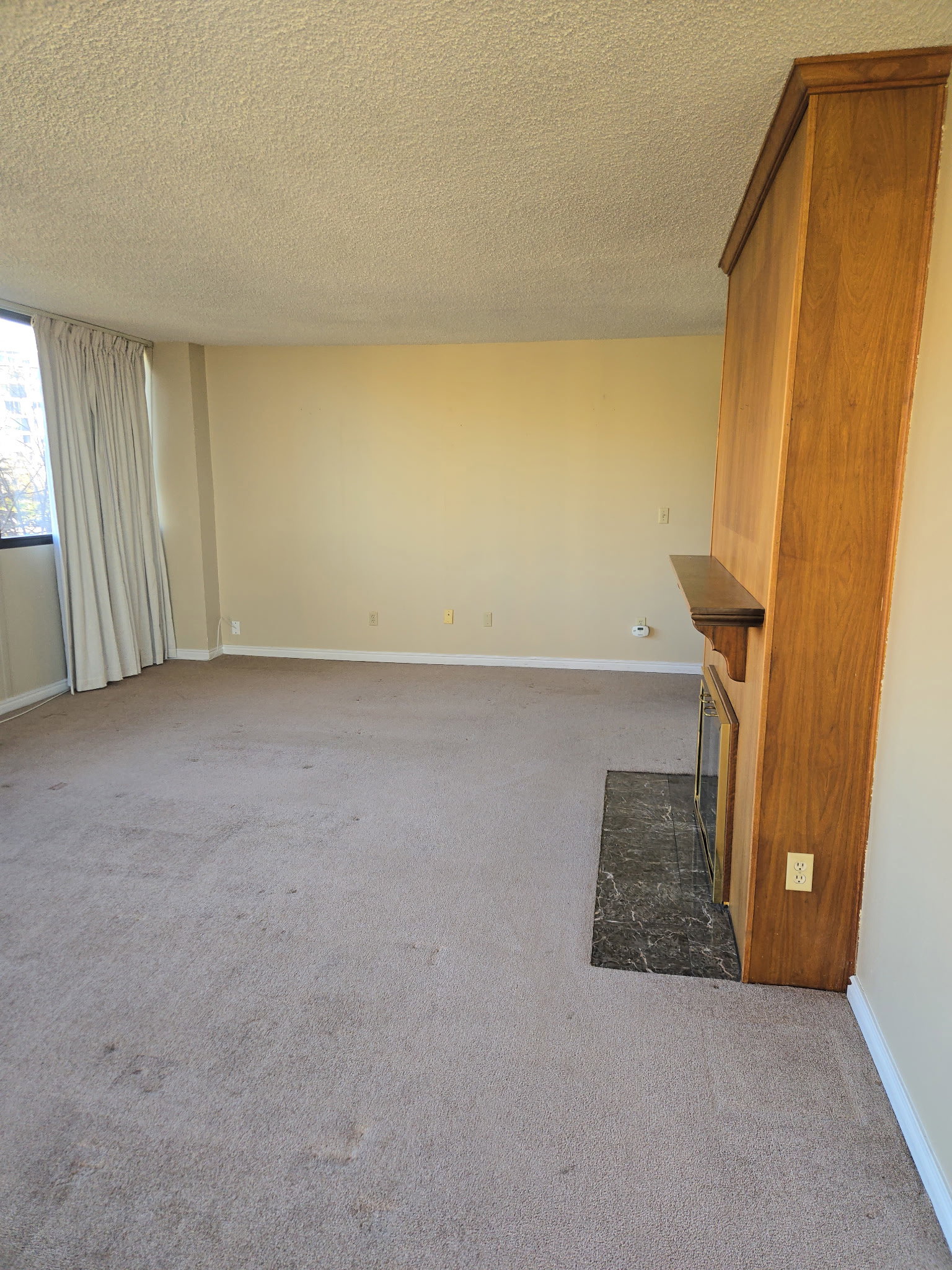 Unfurnished living room featuring light carpet, a fireplace, and a textured ceiling