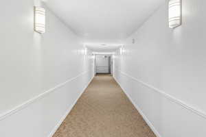 Hallway with light colored carpet and a textured ceiling
