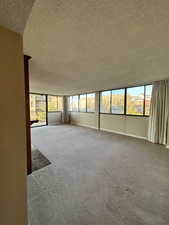 Unfurnished room featuring a textured ceiling and carpet