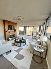 Living room featuring a textured ceiling, carpet floors, and a glass covered fireplace