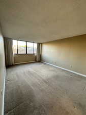 Carpeted empty room featuring a textured ceiling and baseboards