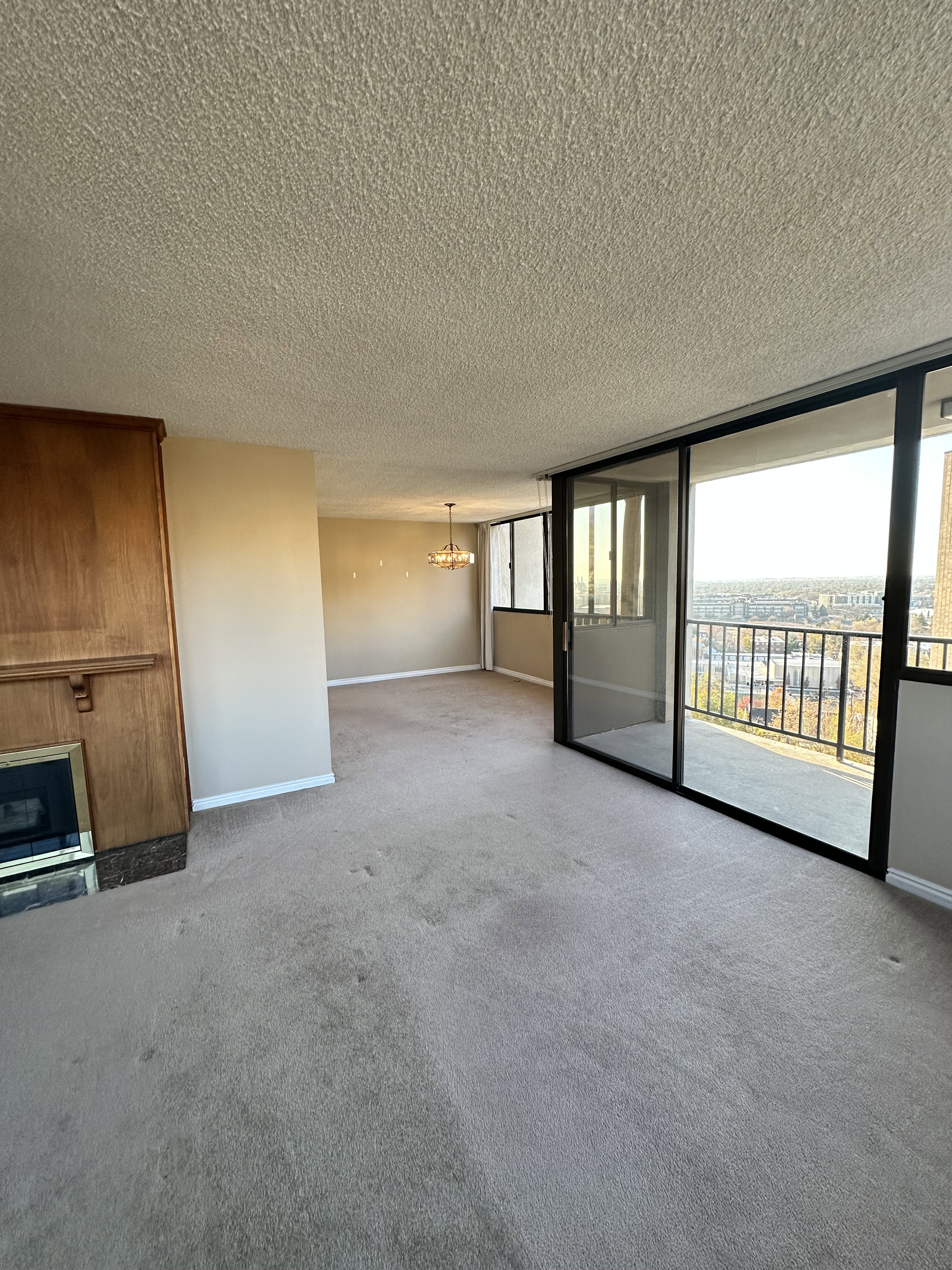 Carpeted spare room featuring a chandelier, a textured ceiling, and a wall of windows