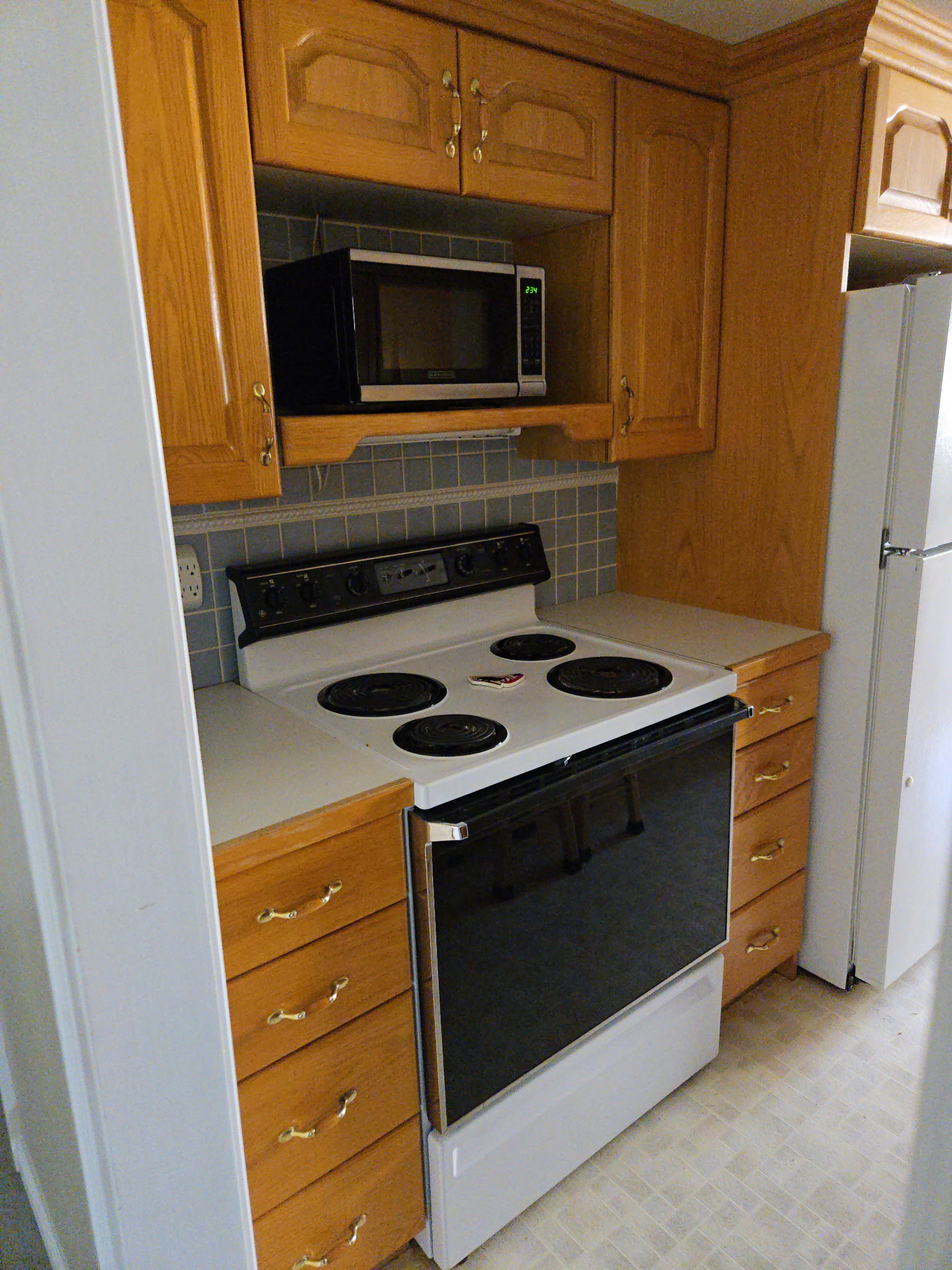 Kitchen featuring white appliances, light countertops, brown cabinets, and backsplash