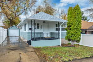 View of front of house with an outbuilding, a porch, a chimney, concrete driveway, and a garage
