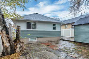 Rear view of house featuring a patio area and a shingled roof