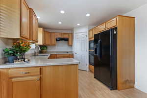 Kitchen featuring black appliances, light countertops, a peninsula, recessed lighting, and light wood-type flooring