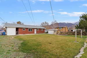 Rear view of house with a mountain view, a storage shed, brick siding, and a patio area