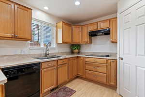 Kitchen featuring black appliances, light countertops, under cabinet range hood, brown cabinetry, and light wood finished floors