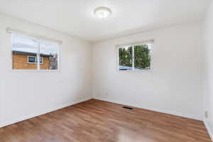 Empty room with light wood finished floors and healthy amount of natural light
