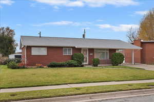 Single story home featuring a front lawn, driveway, roof with shingles, and a carport